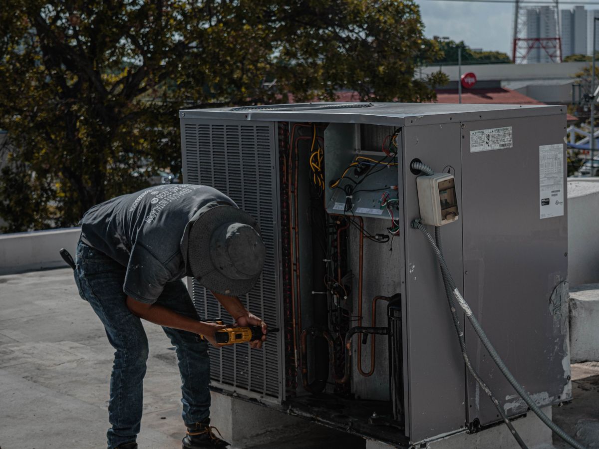 A technician installing and wiring an air conditioning unit