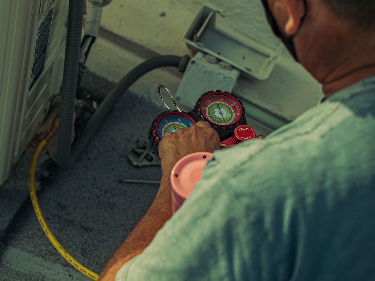 An HVAC technician checking refrigerant with manifold gauges